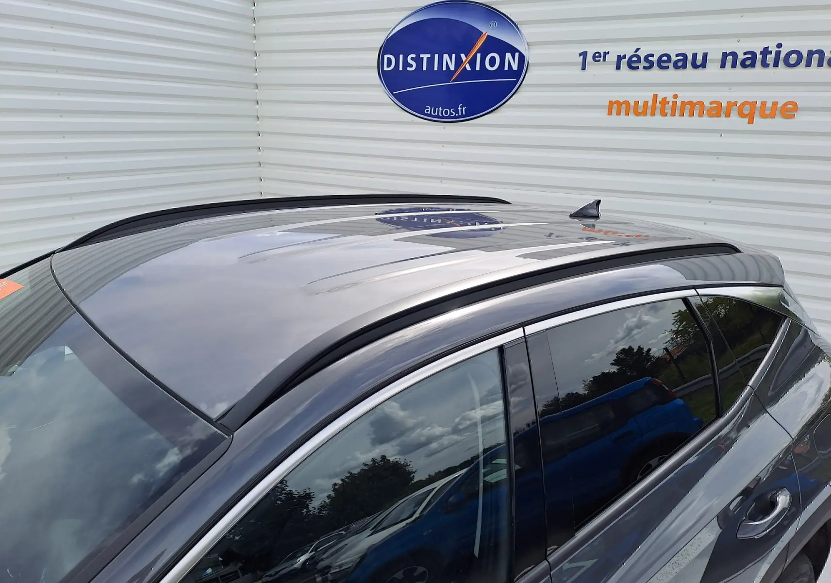 Toit panoramique et antenne requin visibles sur le côté gauche d'un Hyundai Tucson gris Ecotronic 2025.