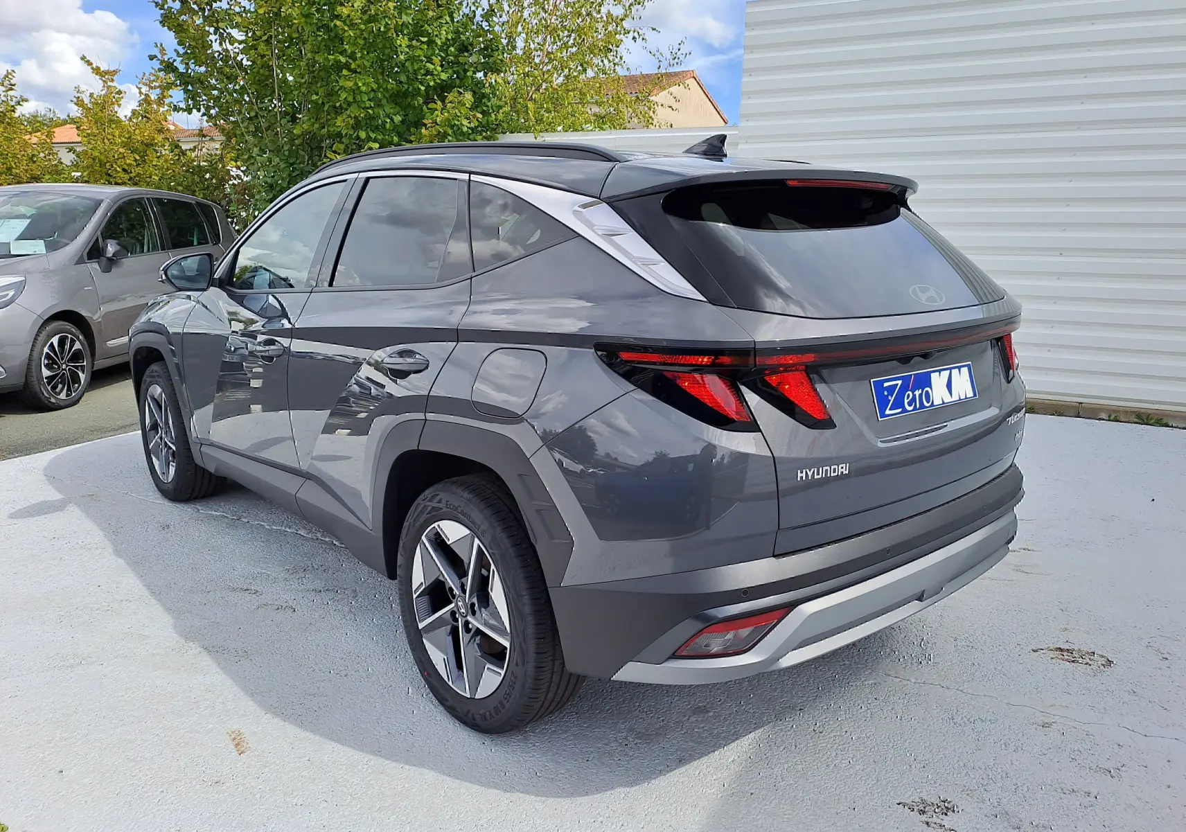 Vue 3/4 arrière droite du Hyundai Tucson 2025 gris Ecotronic avec feux arrière LED et jantes alliage bicolores.