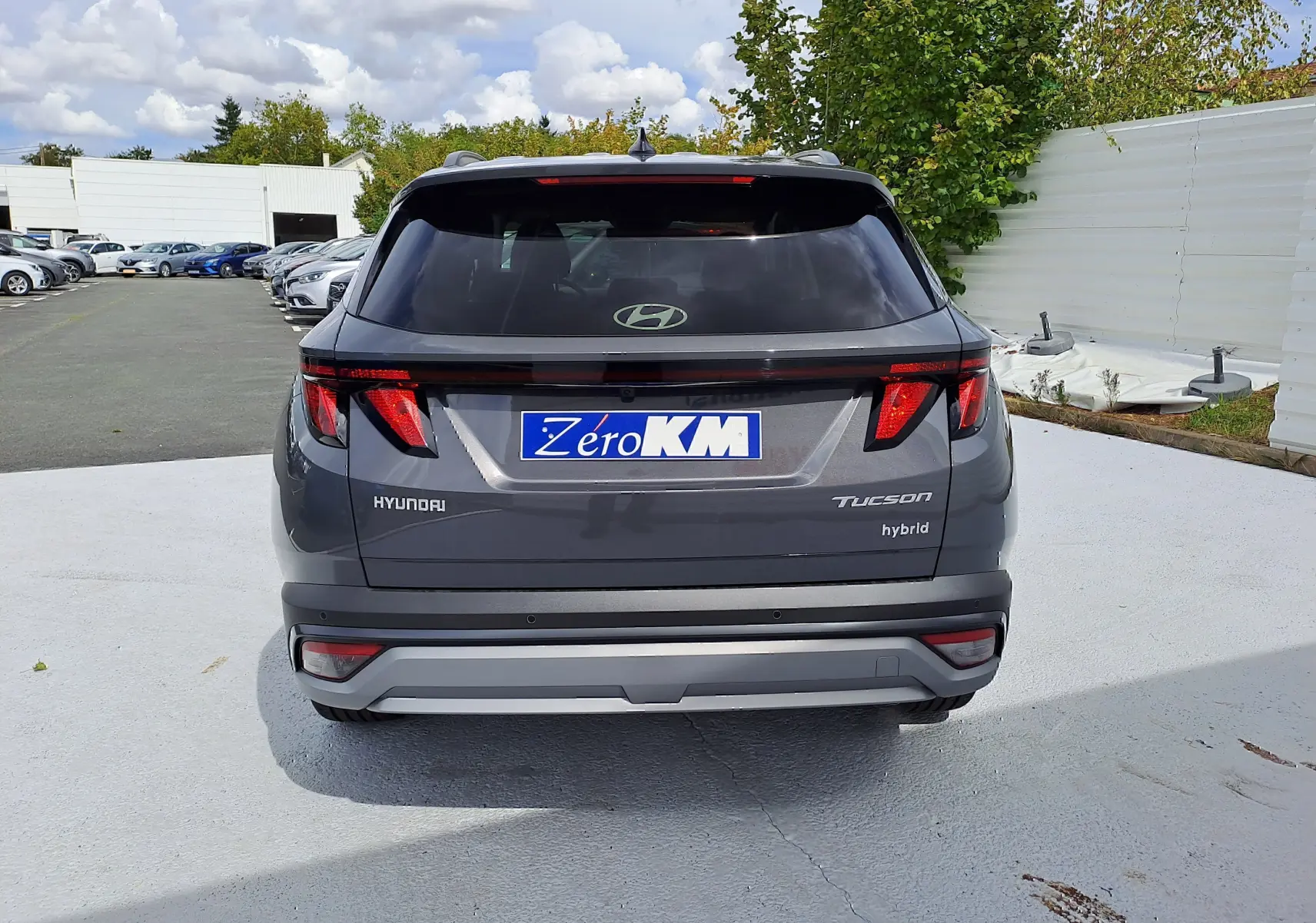 Vue arrière d'un Hyundai Tucson hybride 2025 en gris Ecotronic avec feux arrière LED et badge Tucson hybrid visible.