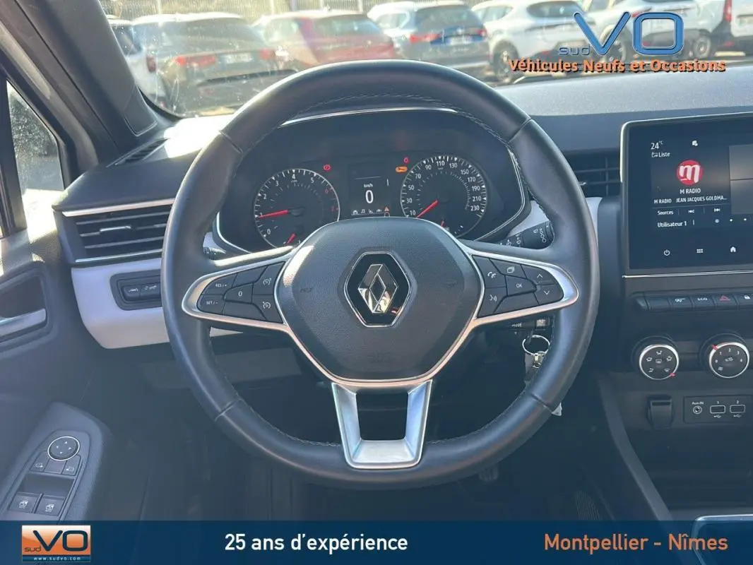 Vue intérieure centrée sur le volant de la Renault Clio blanc 2021 avec tableau de bord et écran tactile visible.