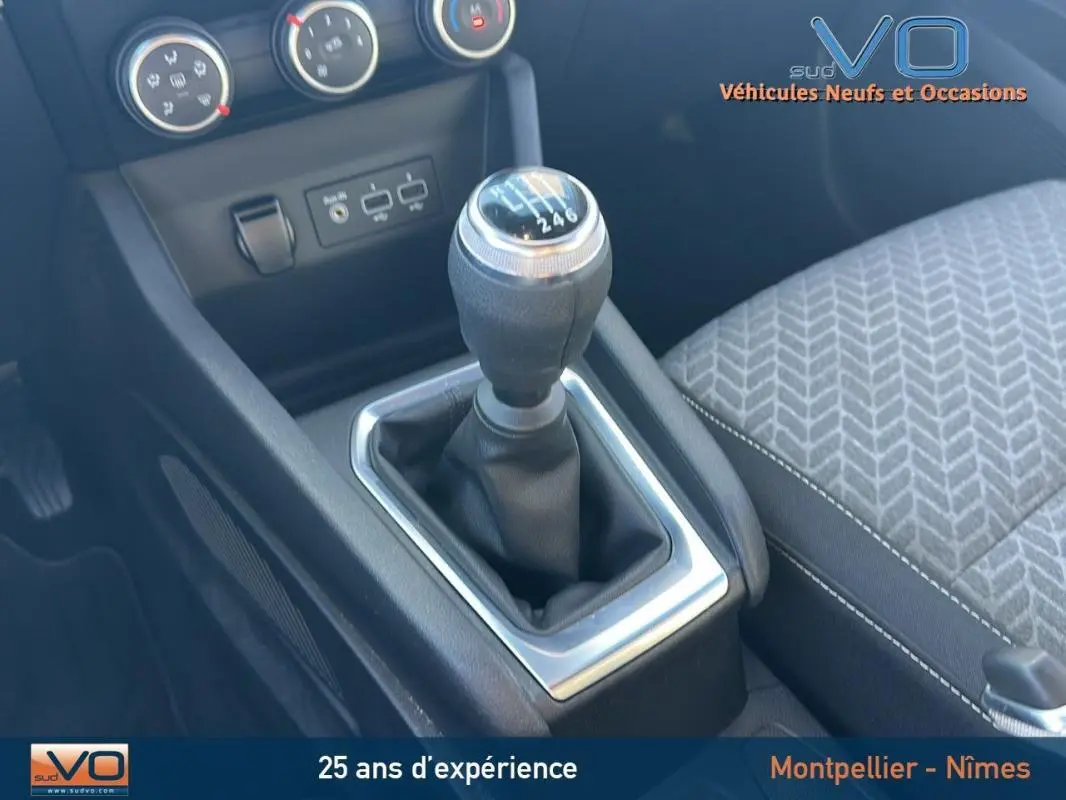 Le levier de vitesses manuel de la Renault Clio V TCe 90 blanc 2021 avec console centrale et siège tissu gris.