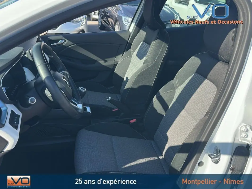 Intérieur de la Renault Clio blanc 2021, vue côté conducteur montrant sièges tissu gris et volant noir.