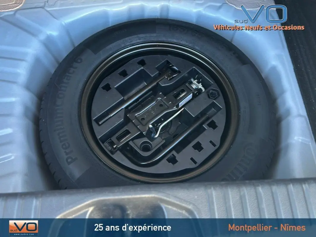 Gros plan sur la roue de secours et les outils de bord dans le coffre d'une Renault Clio blanche V TCe 90 - 21 Limited.