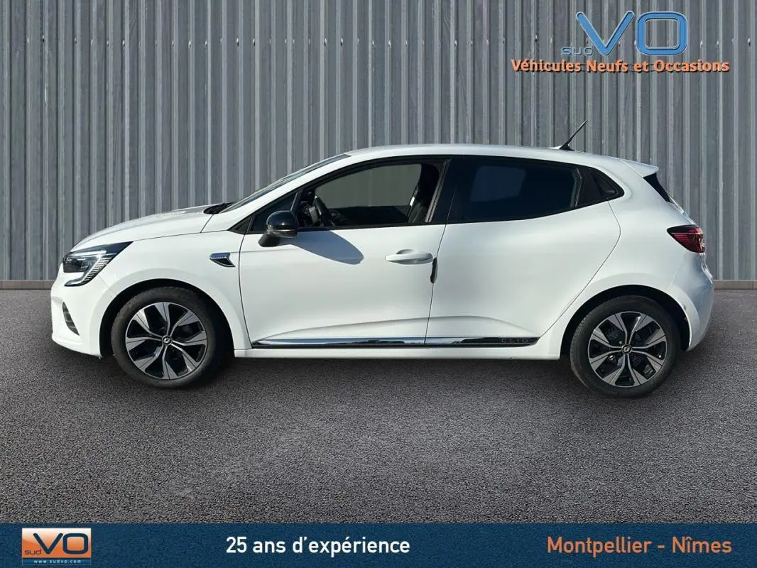 Profil côté gauche d'une Renault Clio blanche V TCe 90 - 21 Limited avec jantes alliage 16 pouces sur fond neutre.