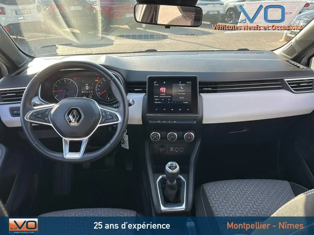 Vue intérieure avant de la Renault Clio blanc, tableau de bord moderne avec écran tactile et volant multifonction.