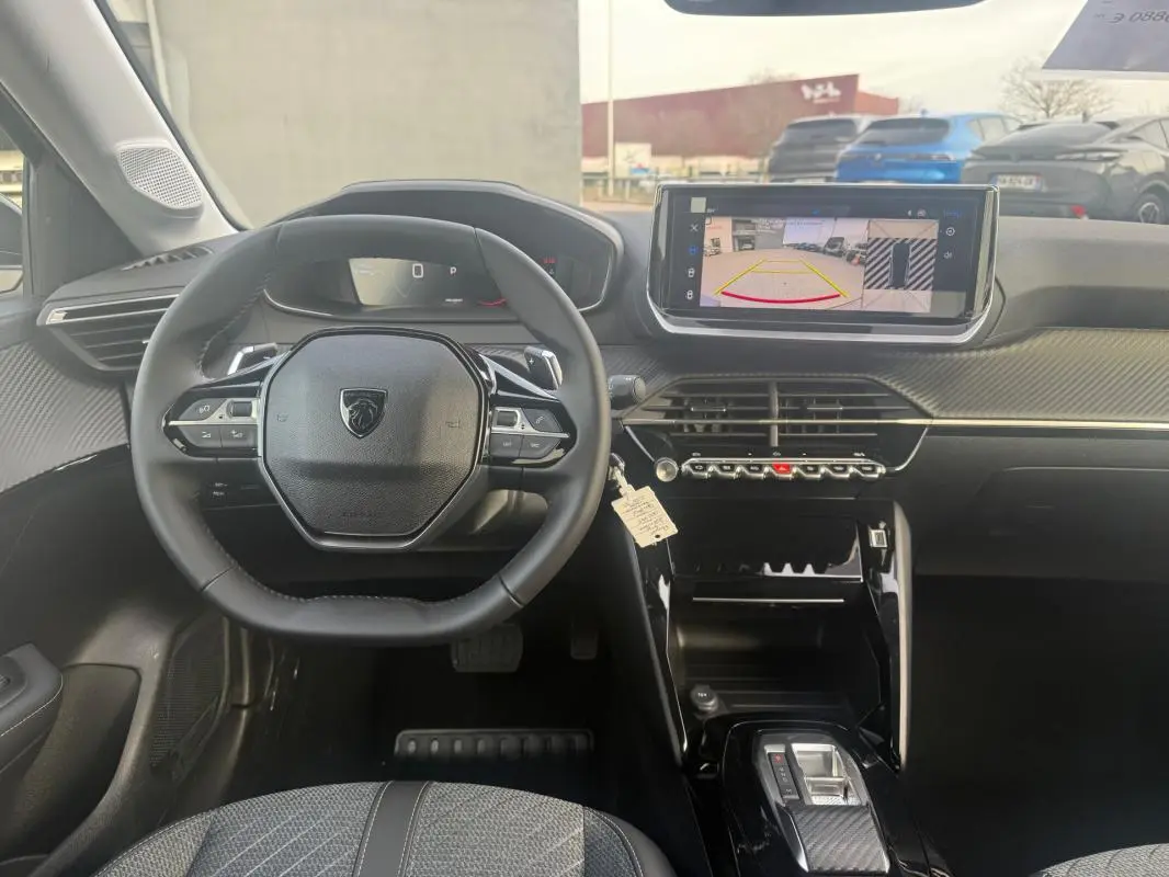 Vue intérieure frontale du poste de conduite de la Peugeot 208 Hybrid 110 gris, avec écran tactile et volant multifonction.