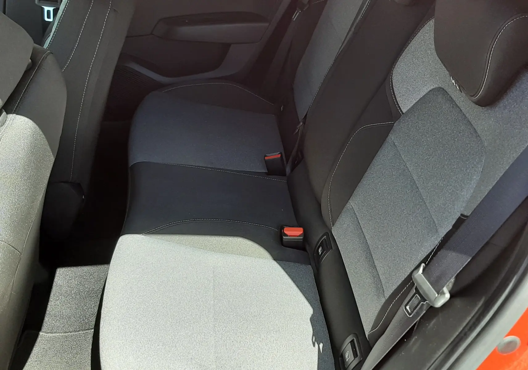 Vue intérieure côté arrière droit montrant la banquette tissu gris et noir d'une Renault Clio V rouge flamme 2024.