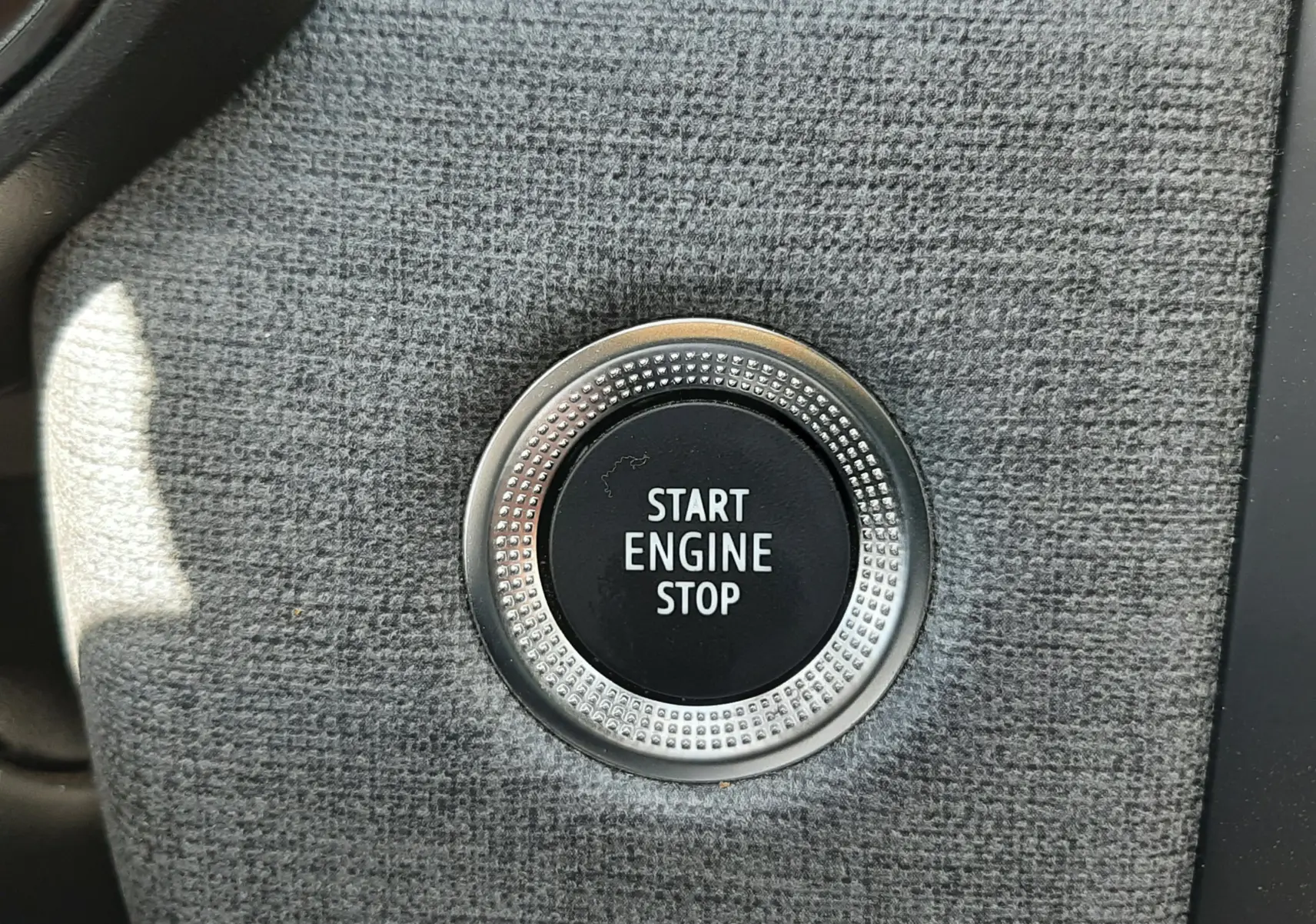 Bouton Start Engine Stop en gros plan sur la console intérieure grise de la Renault Clio V rouge flamme 2024.
