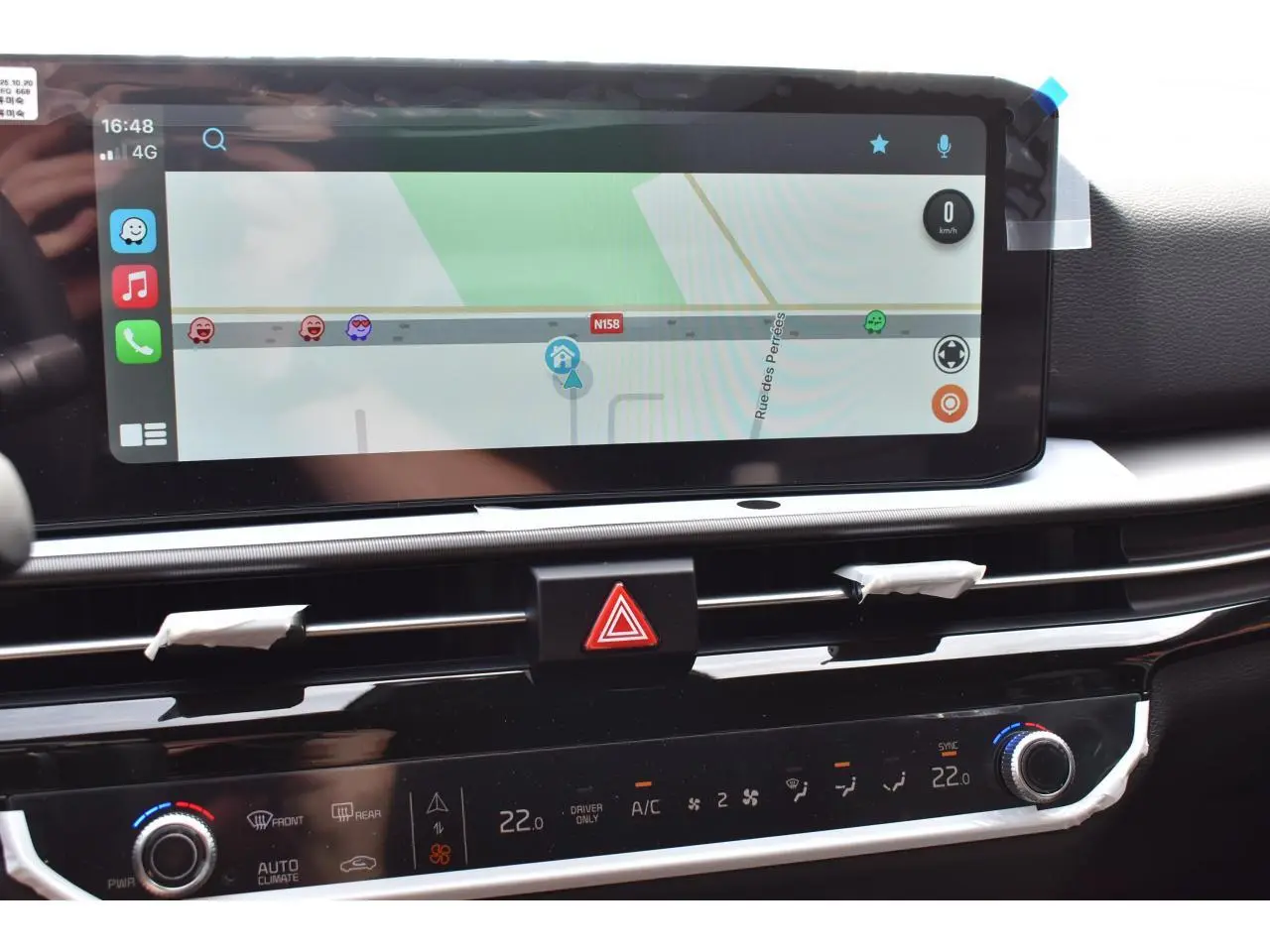 Vue rapprochée de l’écran tactile et de la console centrale du Kia Sportage hybride gris, affichant la navigation et la climatisation.