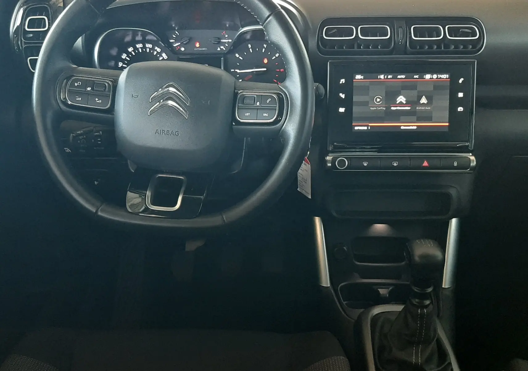 Vue intérieure frontale du tableau de bord et volant noir du Citroën C3 Aircross 2021 avec écran tactile et levier de vitesse manuel.