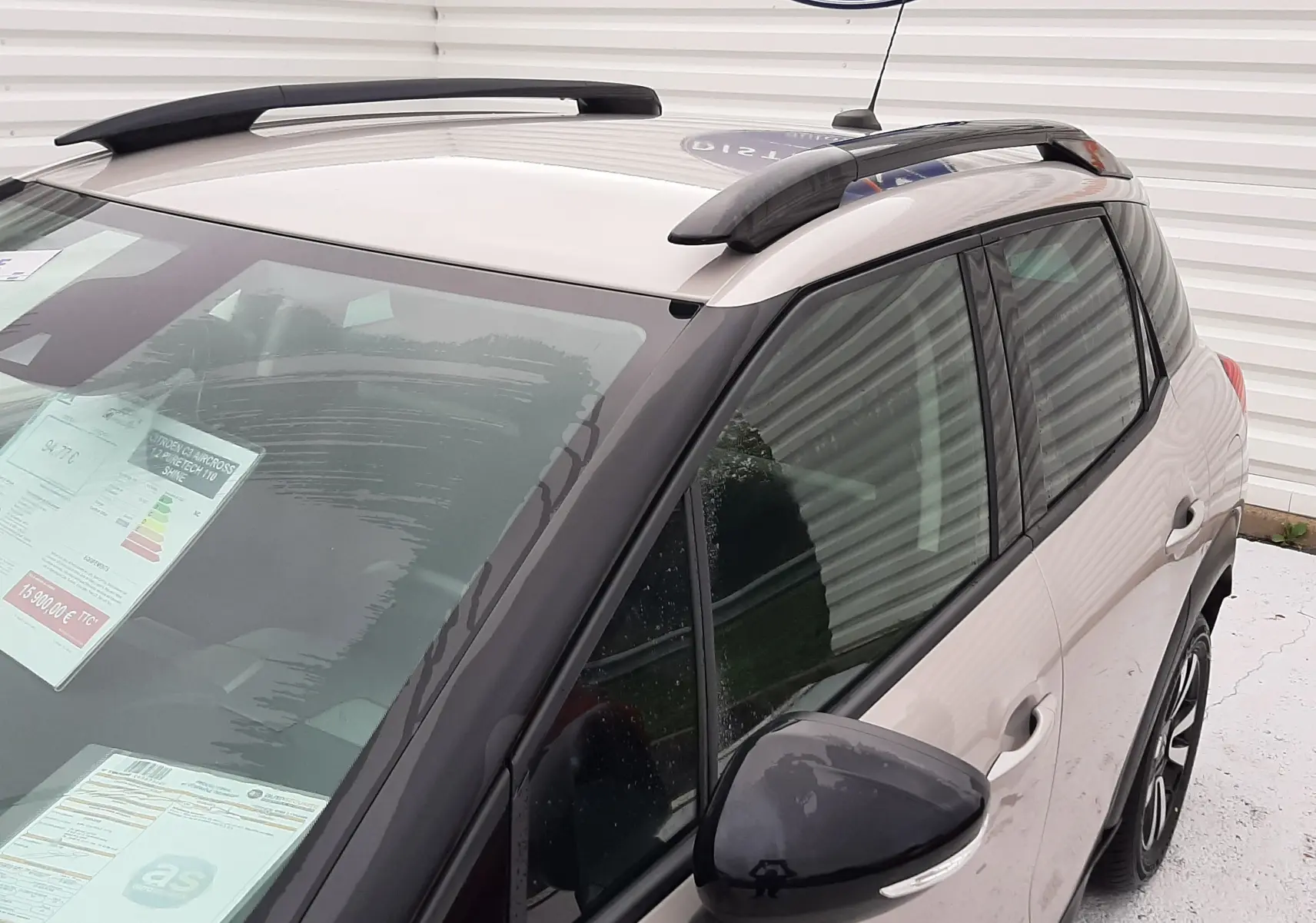 Vue 3/4 avant droit du Citroën C3 Aircross sable métal avec barres de toit noires et vitres teintées.