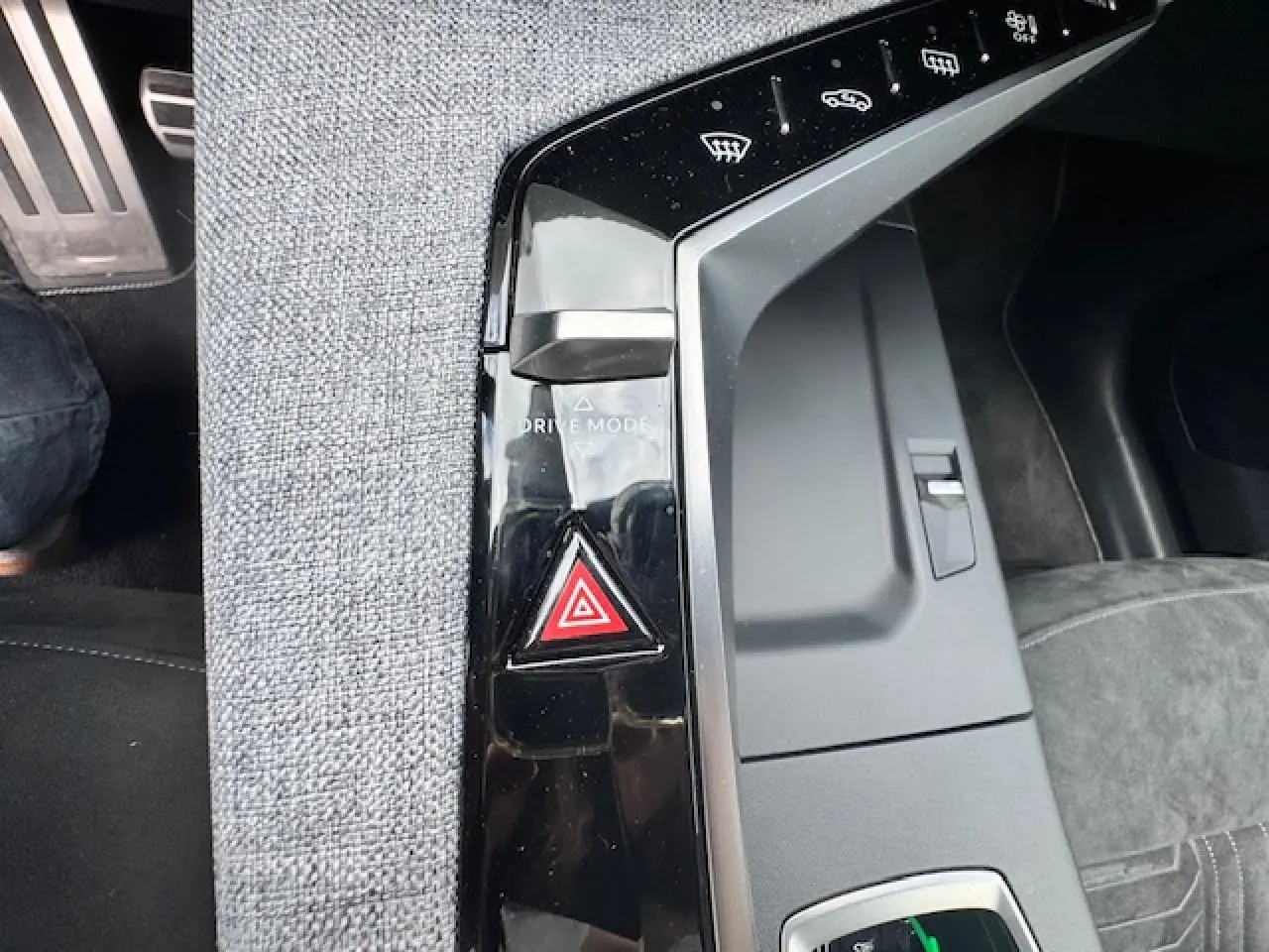 Gros plan sur la console centrale noire brillante avec bouton de mode de conduite et signal d'alarme du Peugeot 5008 gris titane.