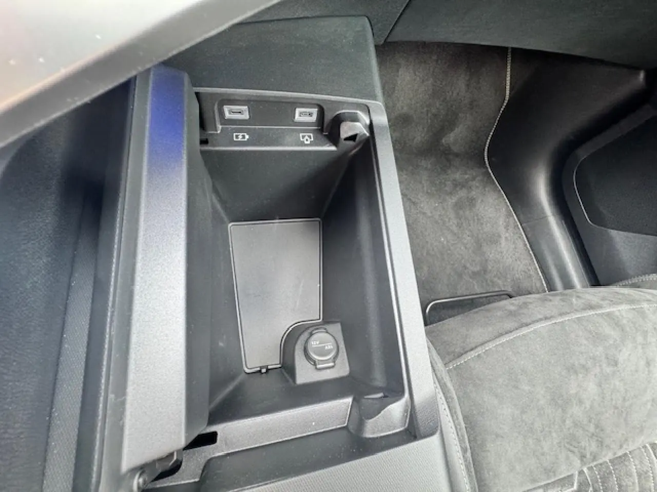 Vue rapprochée de la console centrale noire avec prises USB et prise 12V du Peugeot 5008 gris titane intérieur Alcantara.