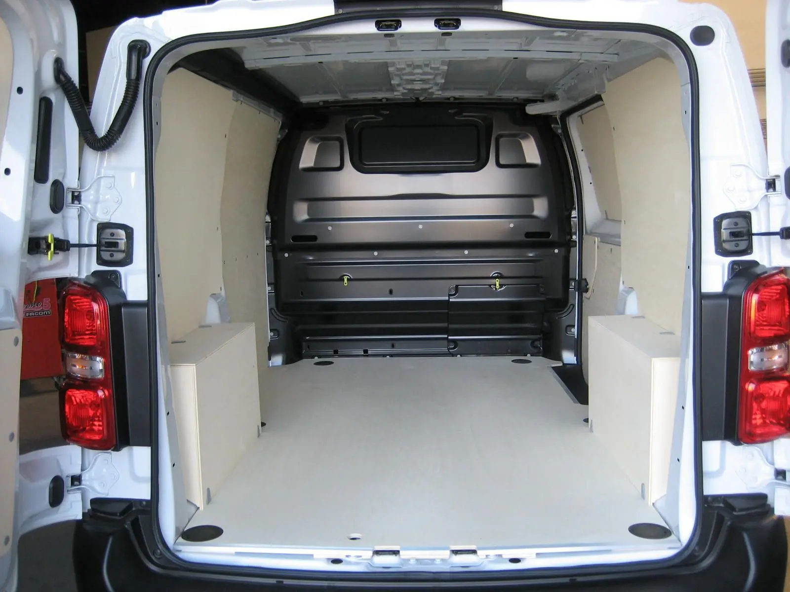 Vue arrière du Peugeot Expert Fourgon blanc 2025 montrant l'espace de chargement vide avec revêtement bois clair.