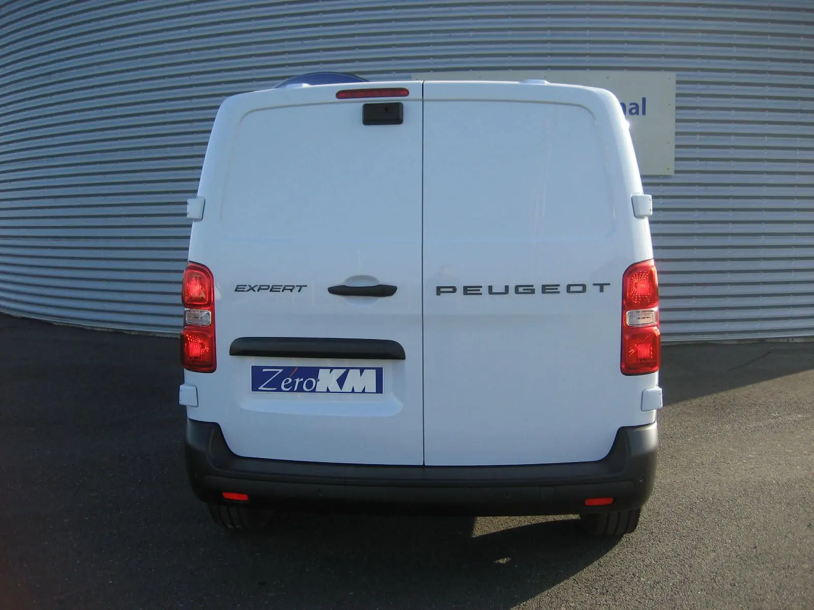 Vue arrière d'un Peugeot Expert Fourgon blanc 2025 avec portes battantes fermées et feux rouges allumés.