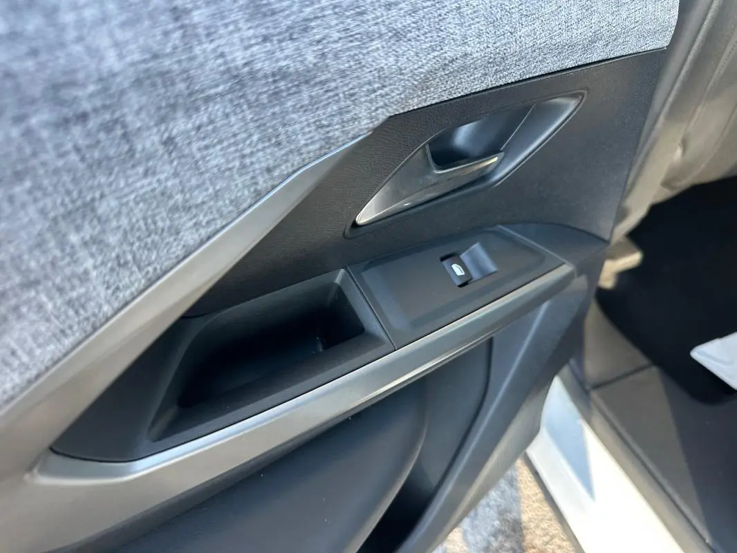 Gros plan sur la porte intérieure côté gauche du Peugeot 3008 blanc, montrant la poignée et les commandes de vitre.