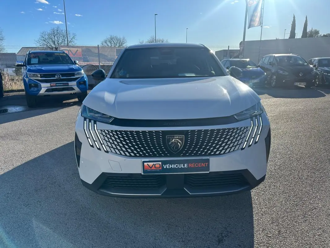 Vue avant d'un Peugeot 3008 Hybrid blanc avec calandre noire et feux LED distinctifs, stationné en extérieur.