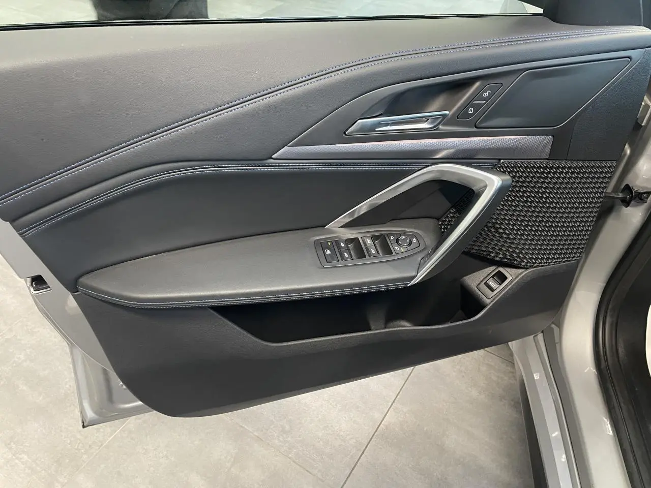 Vue intérieure côté gauche de la porte avant d’un BMW X1 xDrive 20d 2024 en Spacesilber Metallic avec finitions M Sport.