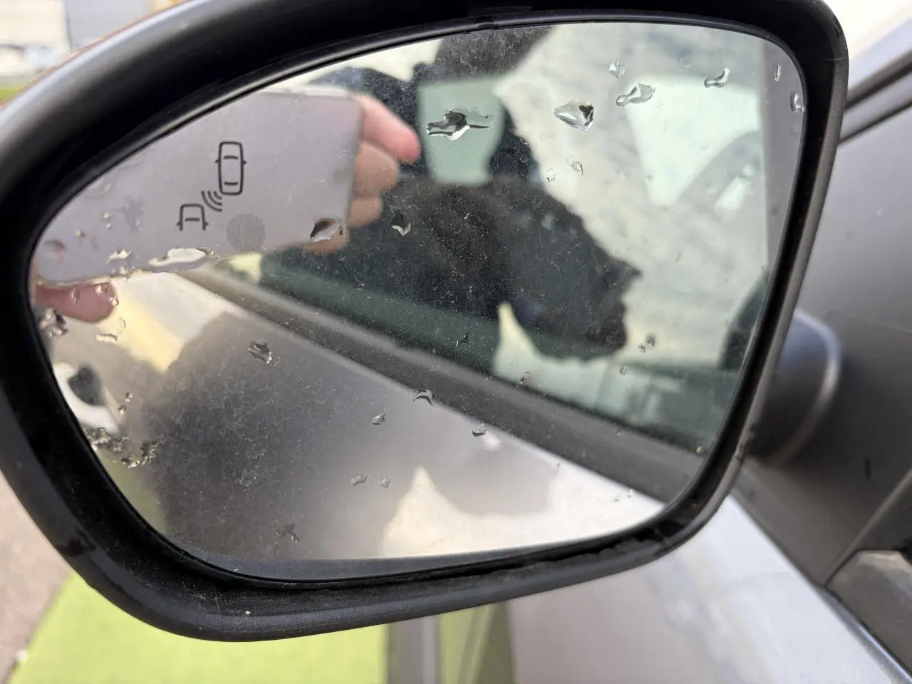 Rétroviseur côté droit gris schiste métal du Dacia Jogger 2025 avec icône de détection d'angle mort visible.