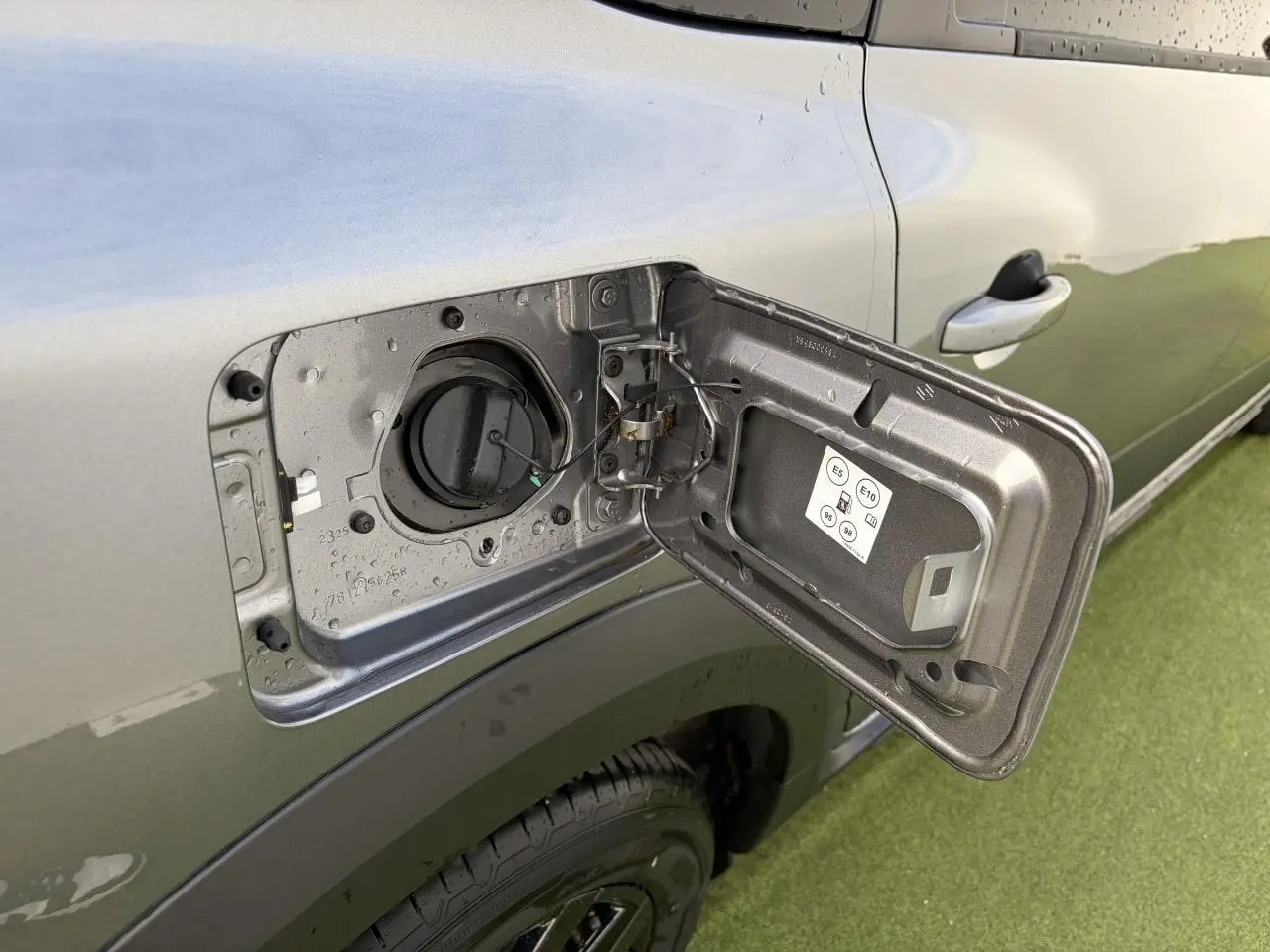 Gros plan sur la trappe à carburant ouverte côté gauche d’un Dacia Jogger gris schiste métal avec porte arrière visible.