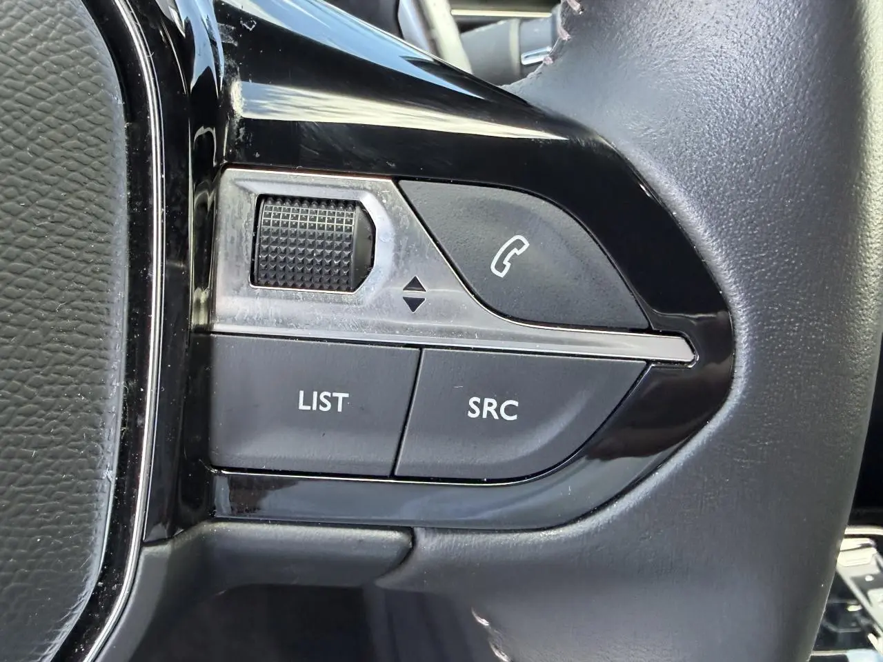 Gros plan sur les commandes du volant côté gauche du Peugeot 3008 noir Perla, boutons appel et réglages audio.