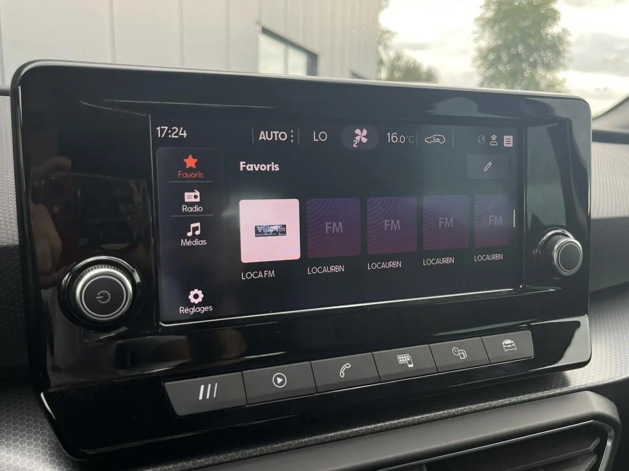 Écran tactile central du tableau de bord du SEAT Leon 2024 noir Minuit, affichant les favoris radio et commandes tactiles.
