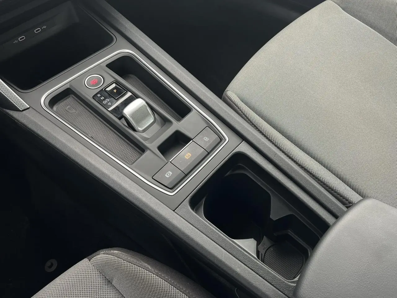 Vue rapprochée de la console centrale noire avec levier de vitesse automatique et accoudoir tissu gris clair du SEAT Leon 2024.