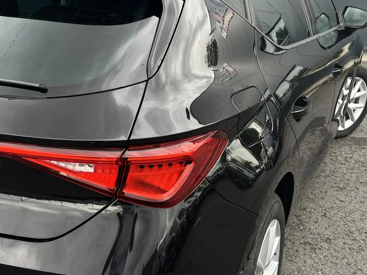 Gros plan sur l'arrière droit noir minuit d'une SEAT LEON 2024, mettant en valeur le feu arrière et la jante alliage.