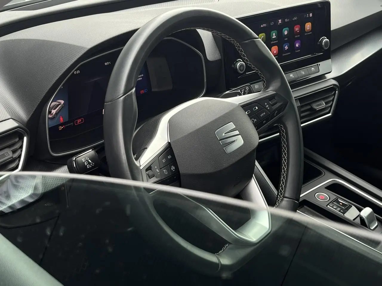 Vue intérieure centrée sur le volant cuir multifonction et l'écran tactile du tableau de bord d'une SEAT LEON 2024.