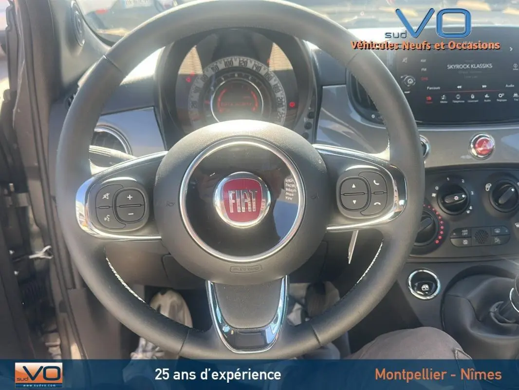 Vue rapprochée du volant et du tableau de bord de la Fiat 500 gris 2023 avec commandes intégrées au volant.