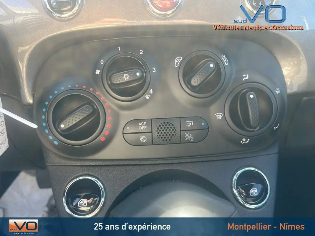 Vue rapprochée des commandes de climatisation et des boutons de fenêtre électrique dans une Fiat 500 grise de 2023.