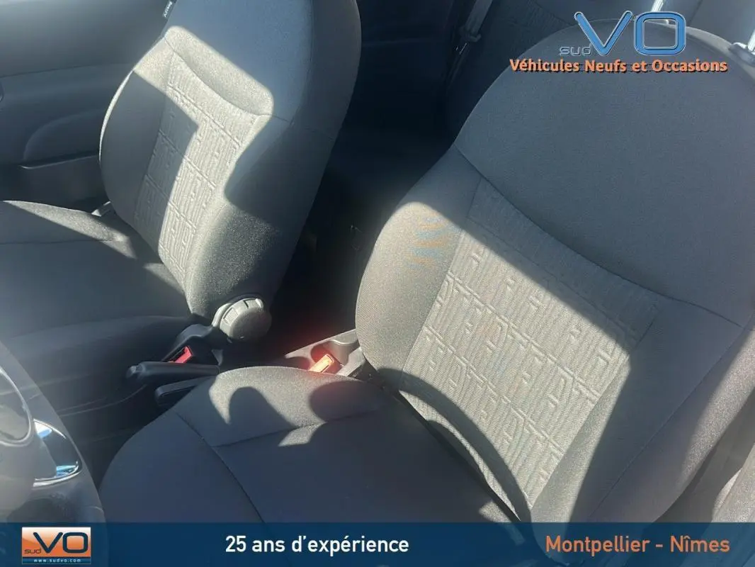 Gros plan sur les sièges avant gris du Fiat 500 2023, version hybride, montrant le tissu texturé et la console centrale.