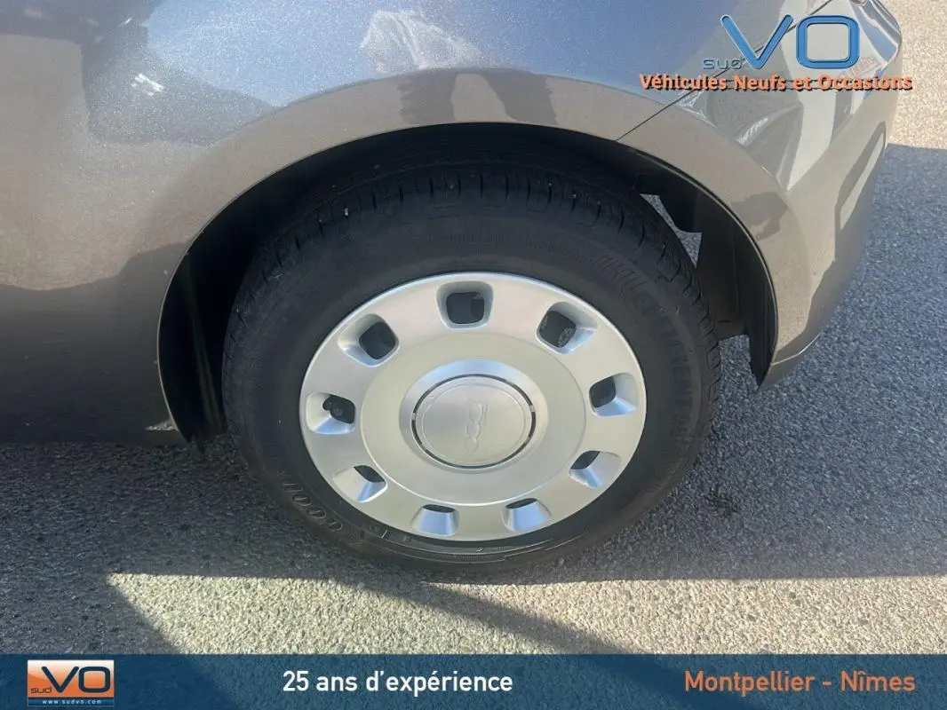 Gros plan sur la roue avant gauche grise d'une FIAT 500 1.0 70 ch Hybride BSG S/S 2023 avec enjoliveur d'origine.