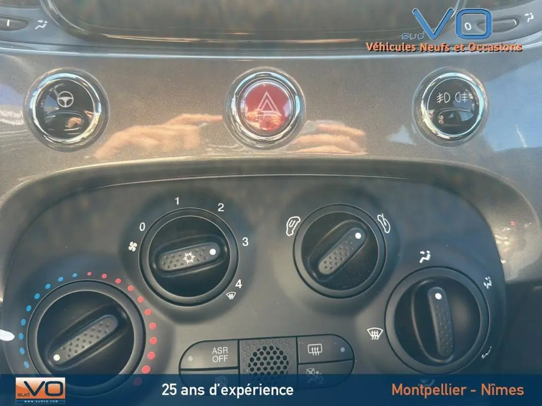 Tableau de bord de FIAT 500 gris 2023 montrant les commandes de climatisation et boutons d'alerte en gros plan.