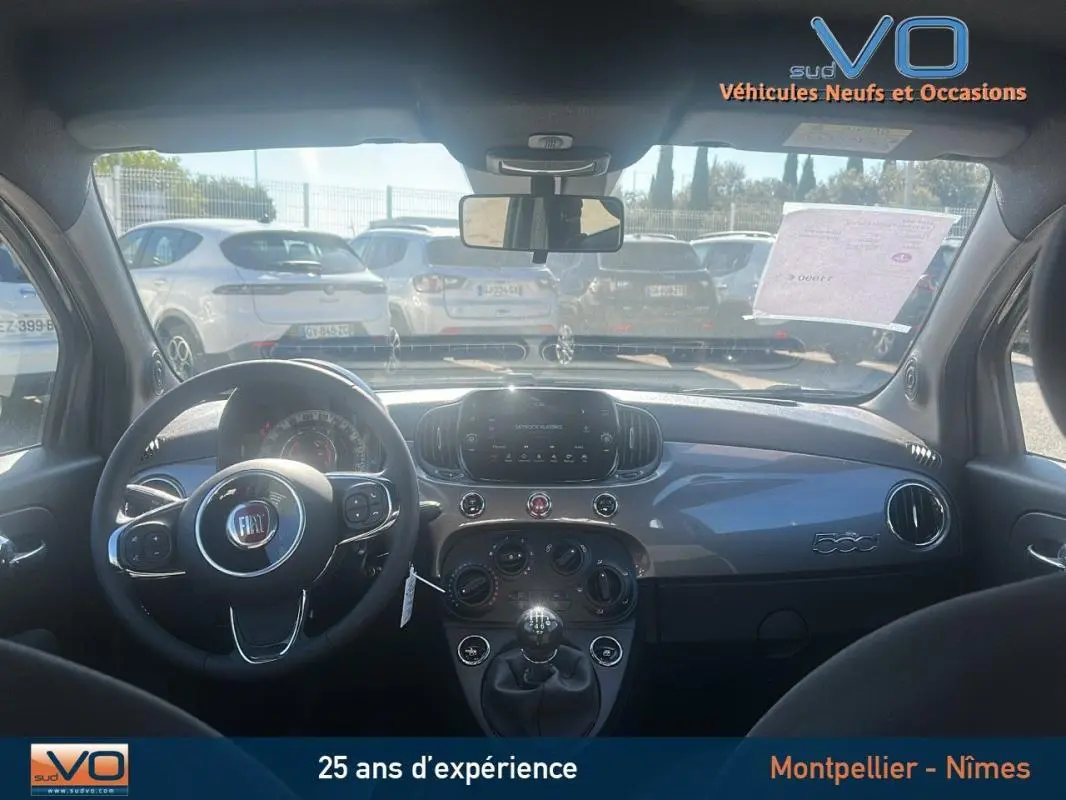 Vue intérieure avant du tableau de bord gris et volant de la Fiat 500 hybride 2023 avec boîte manuelle