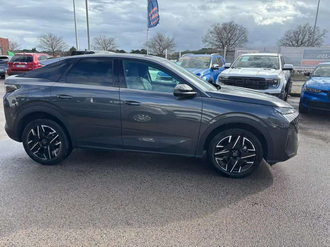 Vue de profil côté gauche d’un Peugeot 3008 Hybrid gris avec jantes alliage 19 pouces, sur parking extérieur.
