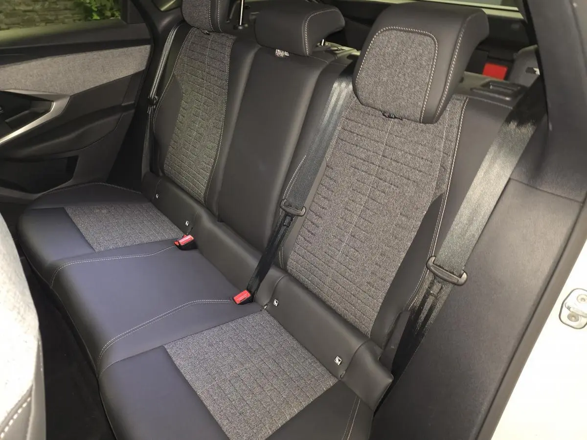 Vue intérieure de la banquette arrière du Peugeot 3008 blanc, avec sellerie tissu gris et cuir noir, ceintures de sécurité visibles.