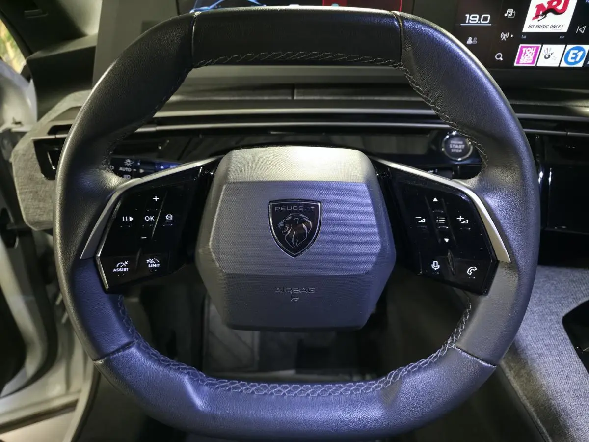 Volant compact cuir noir avec commandes intégrées et logo Peugeot au centre, vue frontale intérieure du 3008 hybride 2025.