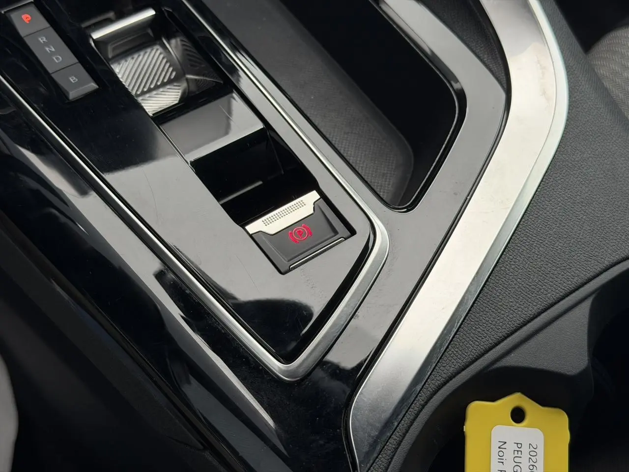 Gros plan sur la console centrale noire du Peugeot 3008 2024, avec frein de stationnement électrique et sélecteur de vitesses.