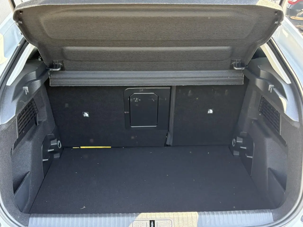 Coffre ouvert de Citroën C4 Hybrid blanc Okénite, montrant un espace de chargement propre et bien agencé.