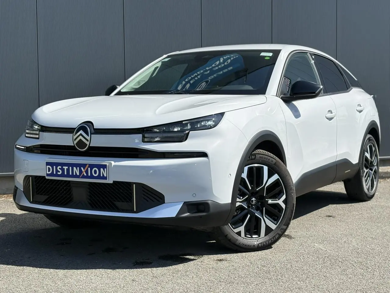 Vue 3/4 avant droite d'une Citroën C4 Hybrid blanche Okénite avec jantes alliage 18'' et rétroviseurs noirs.