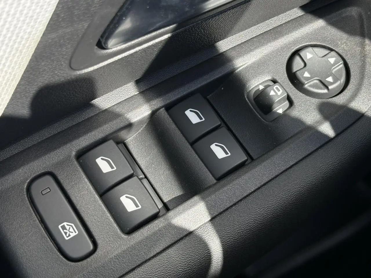 Gros plan sur les commandes de lève-vitres et réglage des rétroviseurs côté conducteur de la Citroën C4 Hybrid blanche.
