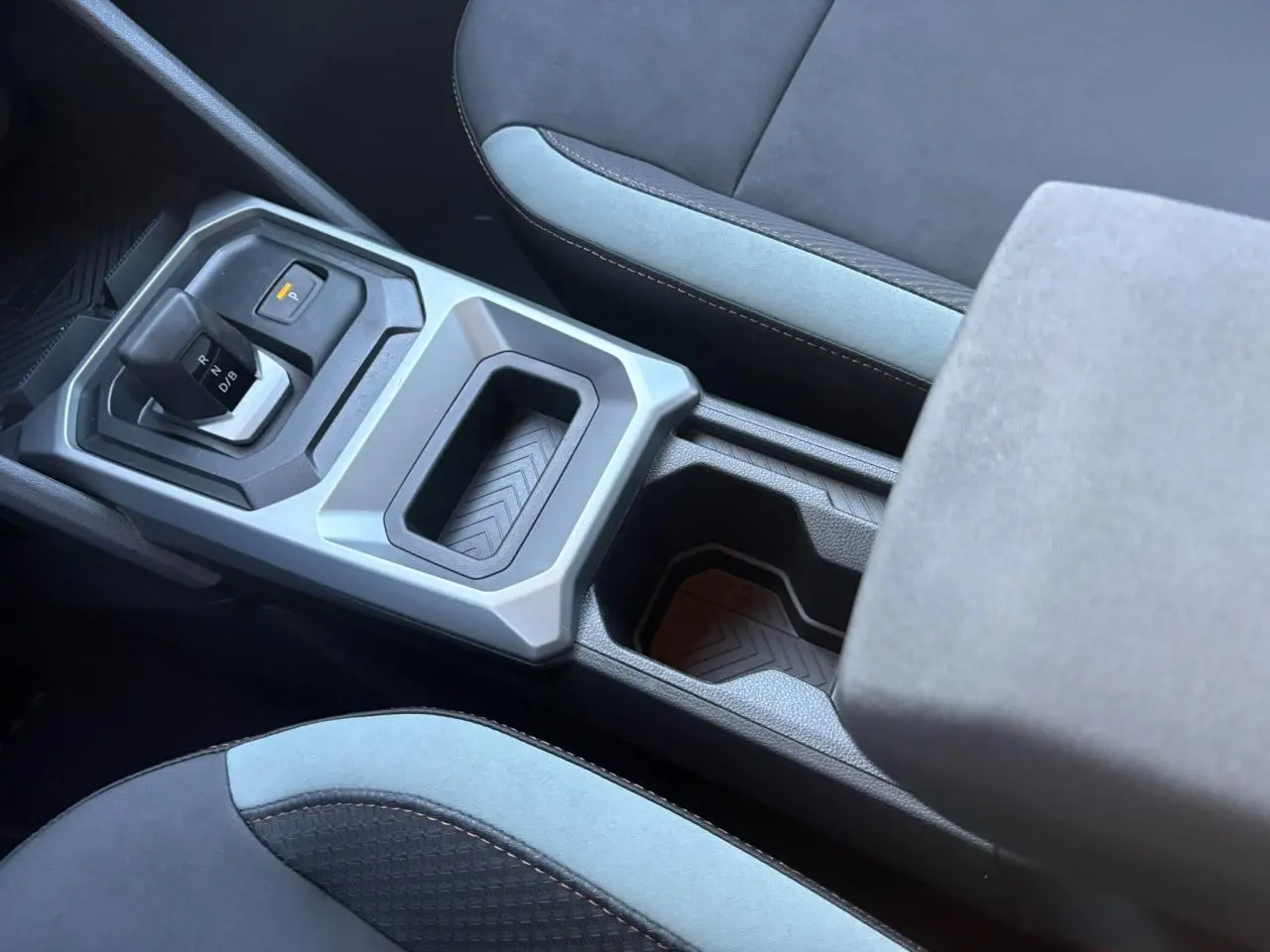 Vue rapprochée de la console centrale gris clair et noire avec levier de boîte auto et accoudoir du Dacia Duster Gris Schiste.