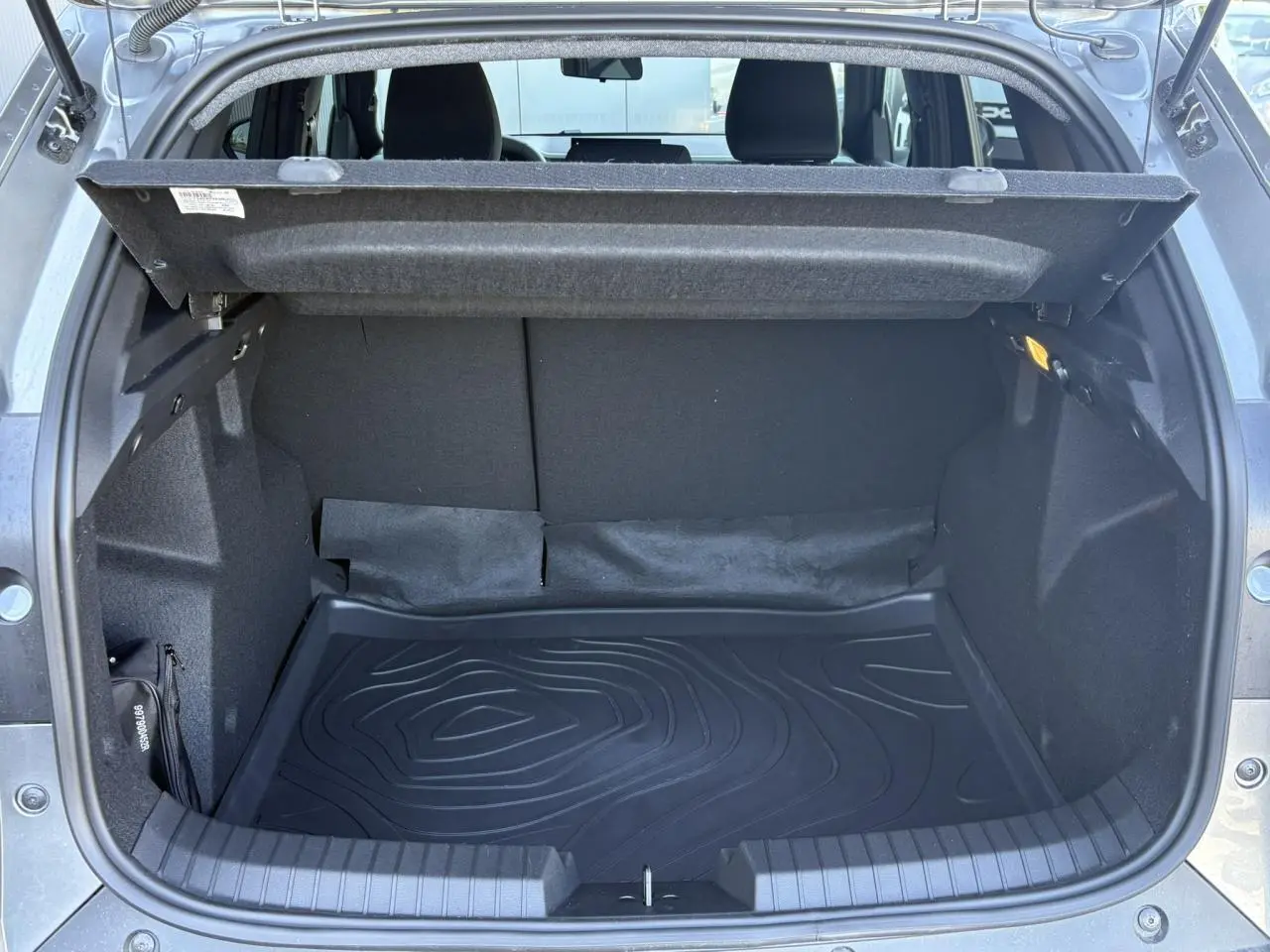 Coffre ouvert vu de l'arrière d'un Dacia Duster Gris Schiste, montrant l'espace de chargement vide et la protection de coffre.