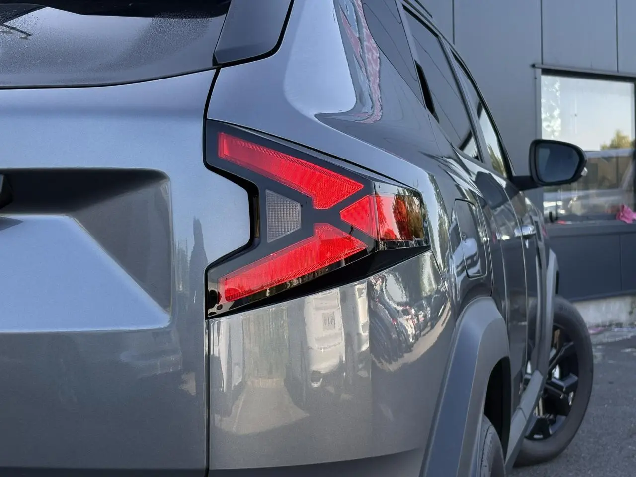 Gros plan sur le feu arrière droit du Dacia Duster 2026 gris schiste, avec jante alliage noire et carrosserie brillante.