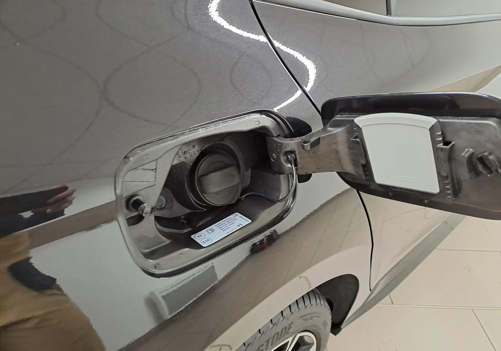 Gros plan sur la trappe à carburant ouverte côté gauche de la Skoda Fabia 2024 noire Magic Nacré.