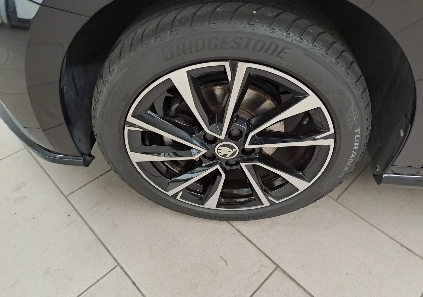 Gros plan sur la roue avant gauche d'une Skoda Fabia 2024 noire avec jante alliage bicolore et pneu Bridgestone.