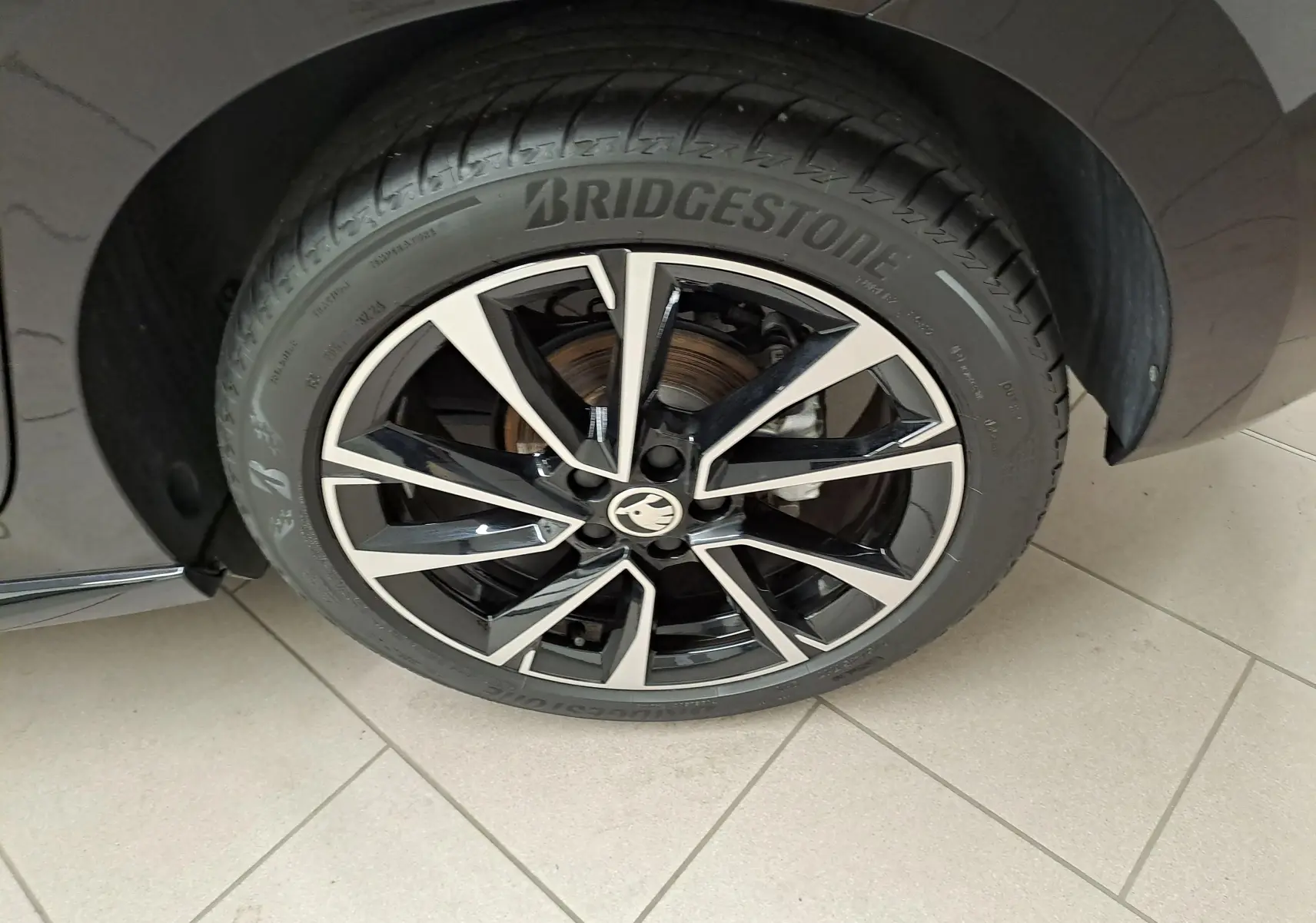 Gros plan sur la jante noire et argentée de la roue avant gauche d'une Skoda Fabia 1.5 TSI 2024 Noir Magic Nacré.