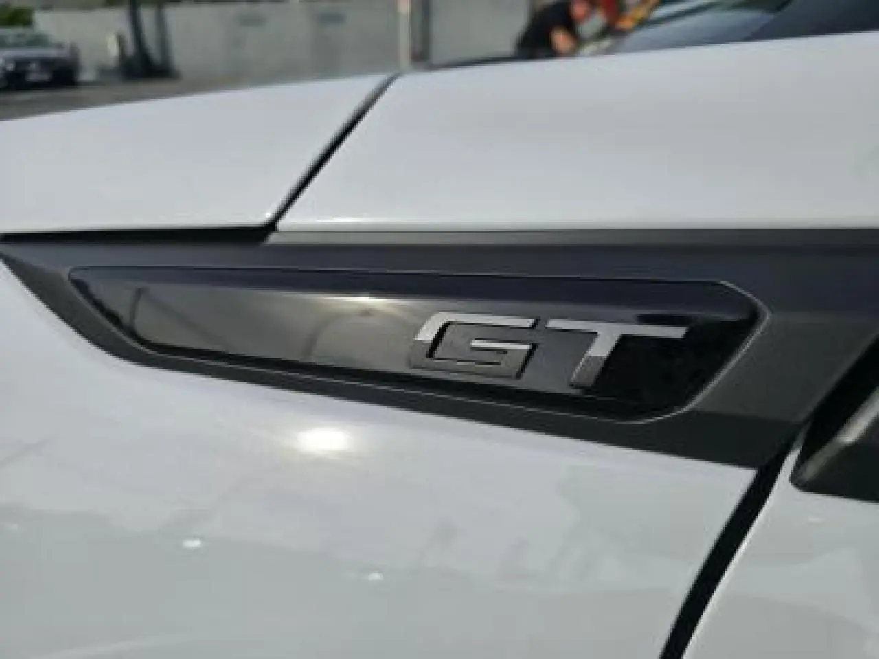 Gros plan sur l’inscription HYBRID noire sur la carrosserie blanche d’un Peugeot 2008 2025.