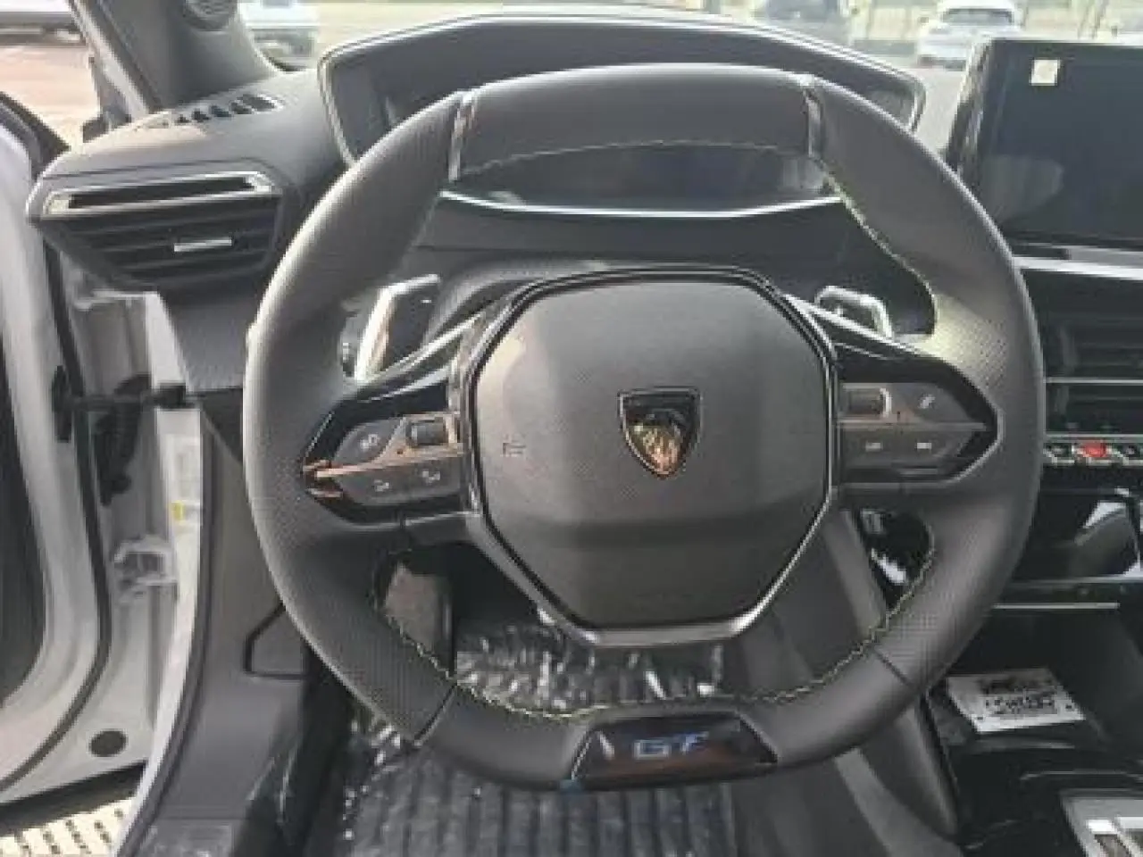 Porte côté gauche ouverte d’un Peugeot 2008 blanc Okenite, intérieur noir avec insert carbone et haut-parleur intégré.